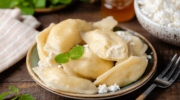 Тарелка аппетитных вареников, политых маслом и посыпанных шкварками